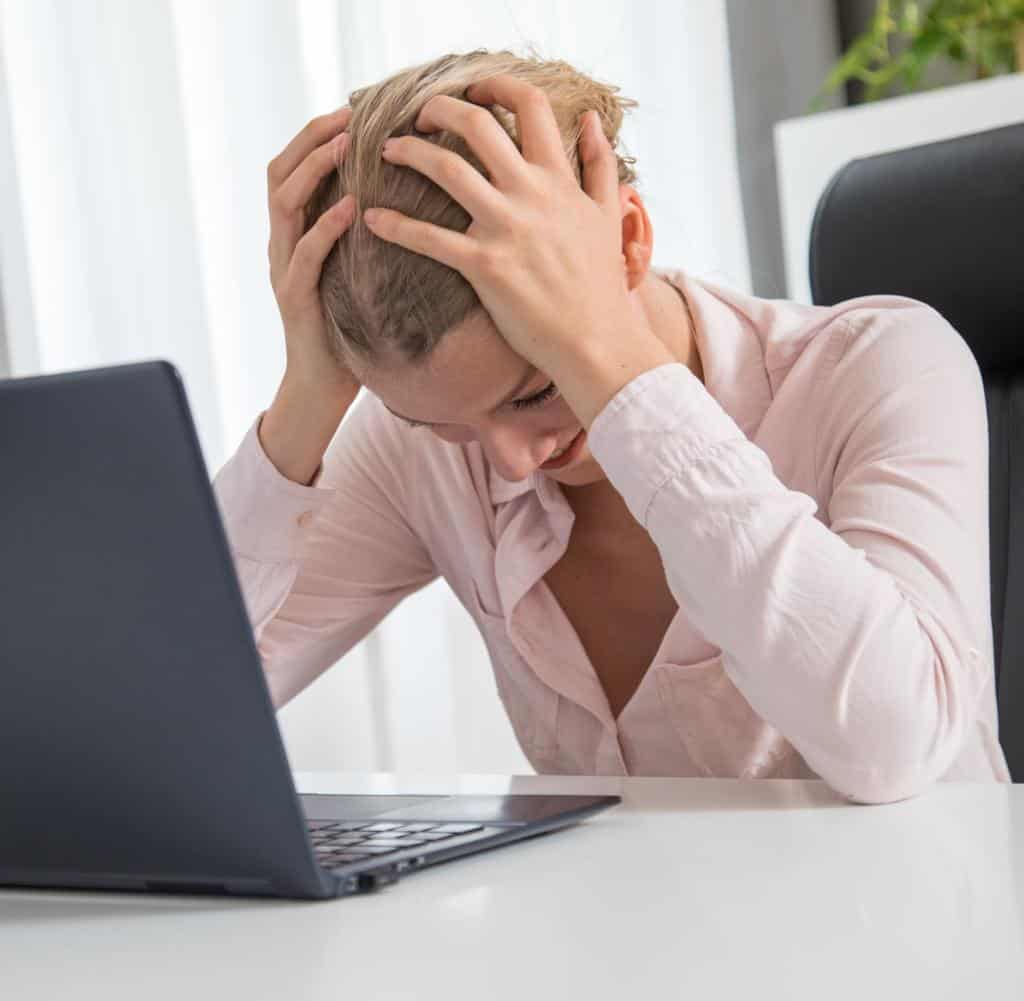Frau am Laptop mit Stresssymptomen – psychische Belastung im Homeoffice